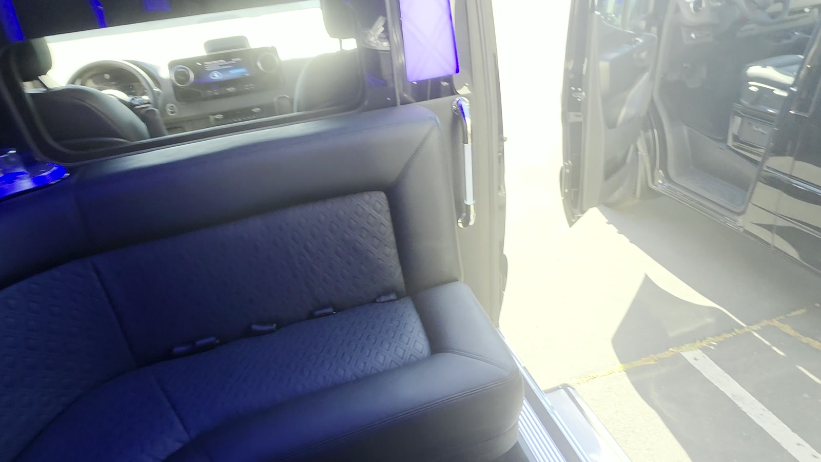 Open side door of the Sprinter showing leather and cloth bench seating with the front cab beyond